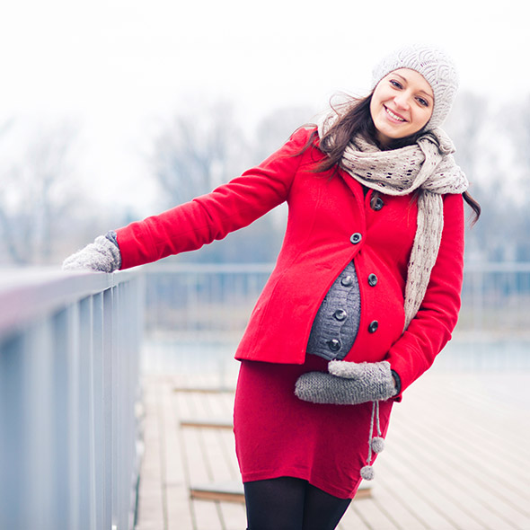 Eine schwangere Frau hält ihren Bauch und ist glücklich