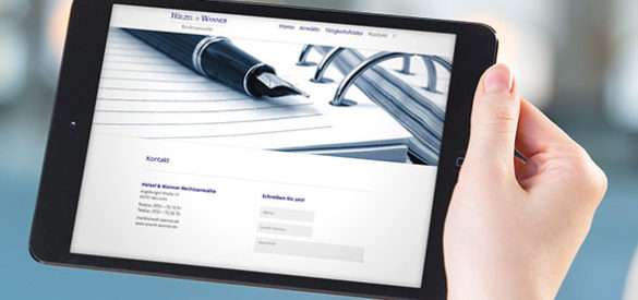 Eine Hand hält ein Tablet auf der die responsive Website von Hoelzel und Wanner zu sehen ist